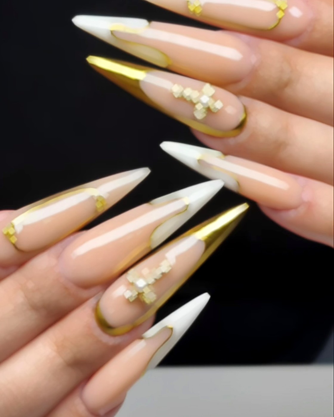 Long nude stiletto nails with white and gold chrome French tips and gold cross charms