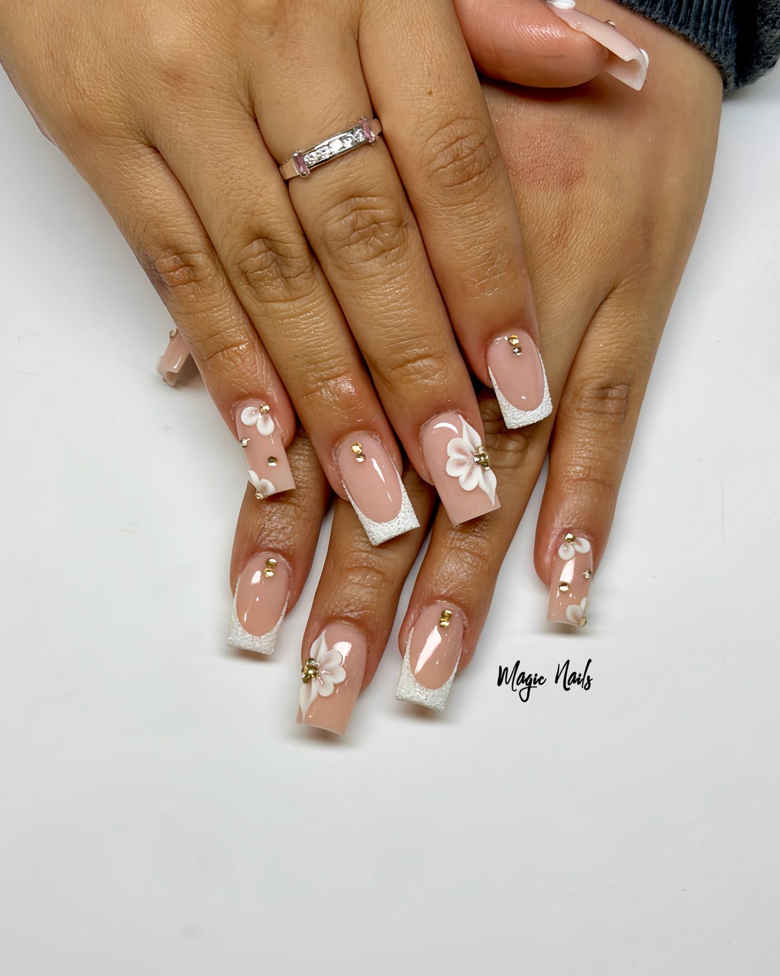 Soft nude square nails with white French tips and delicate white flower accents